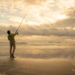 Male Surfcast Fishing During Sunset