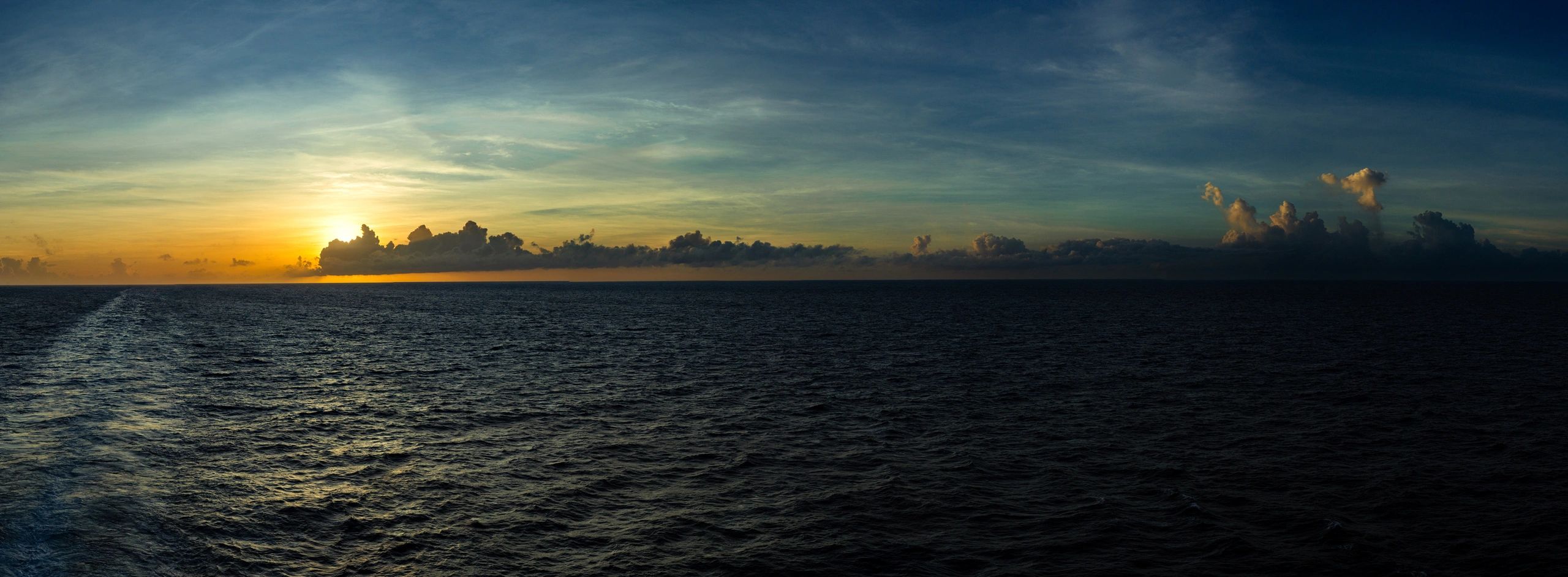 Ocean horizon at sunset with a boat wake